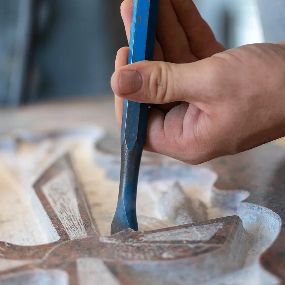 Kaukasischer Mann hämmert einen Grabstein in einer Werkstatt